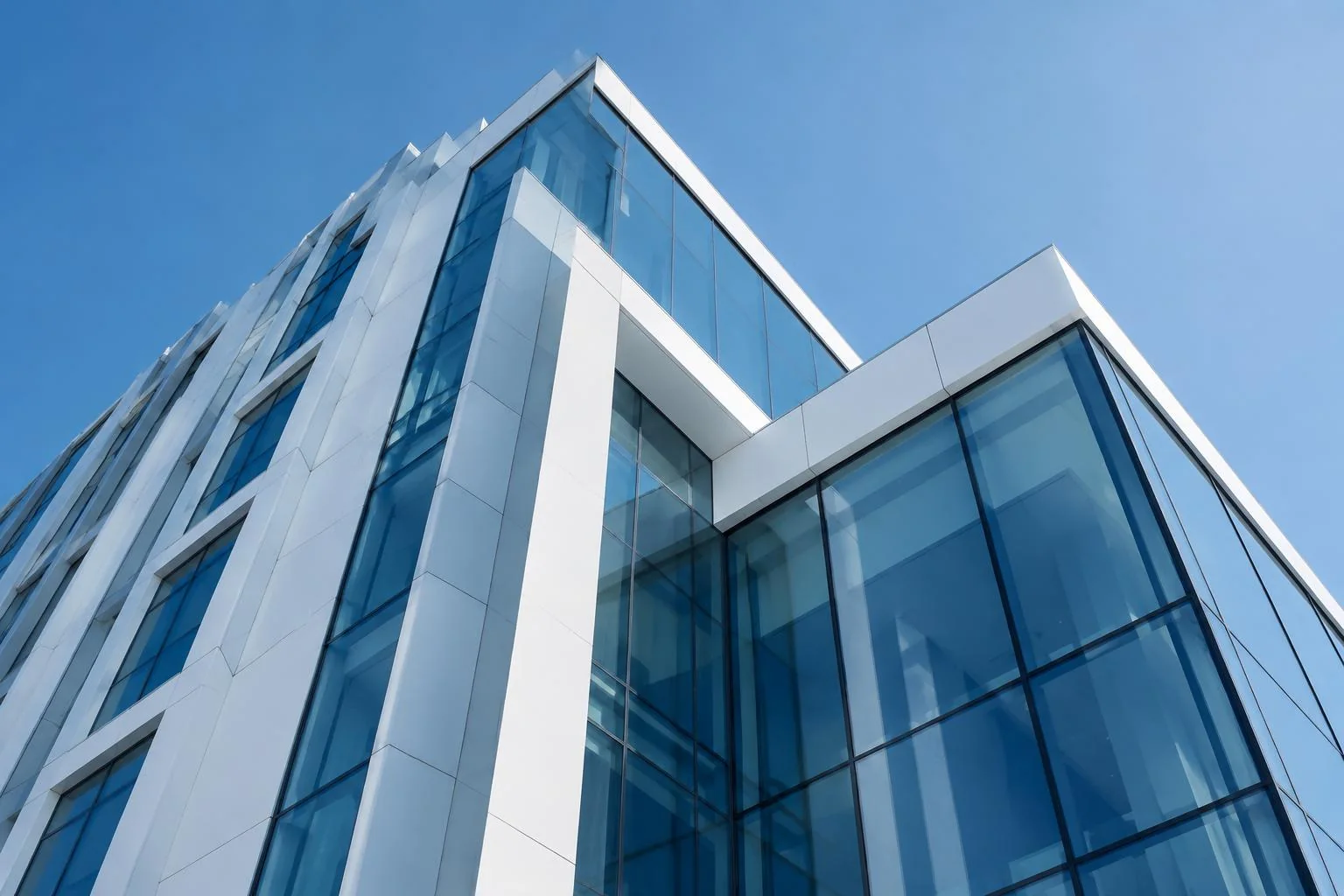 Façade architecturale contemporaine en verre et acier blanc sous un ciel bleu